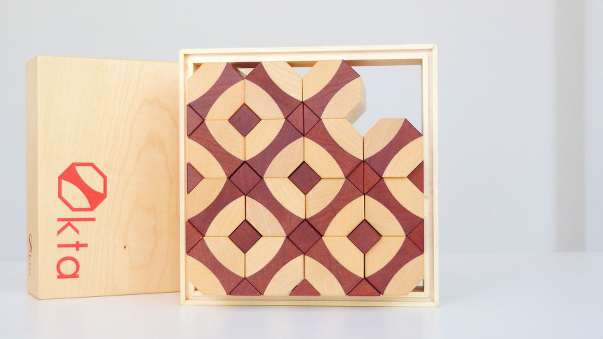Nun ist die Spielbox fast vollständig mit den Bausteinen ausgefüllt. Ihre verschiedenfarbigen Holzarten bilden ein Muster.