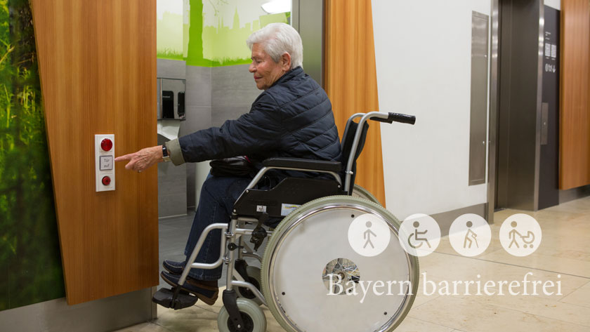 Ältere Dame im Rollstuhl betätigt elektrischen Türöffner.