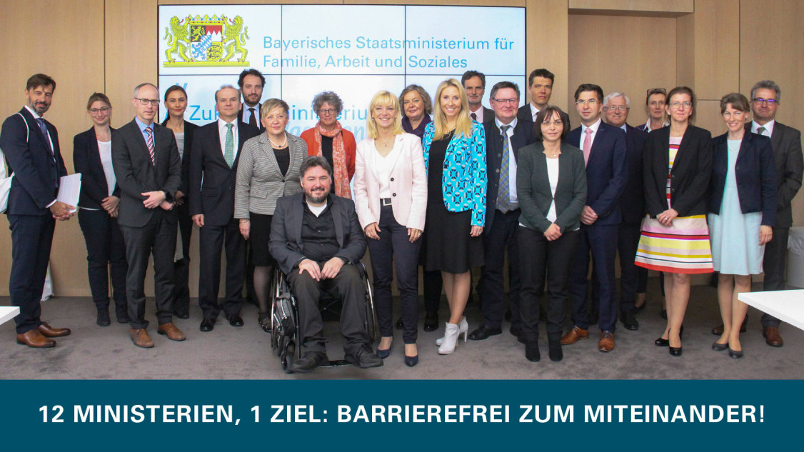 Gruppenfoto im Bayerischen Sozialministerium mit Text: „12 Ministerien, 1 Ziel: barrierefrei zum Miteinander!“