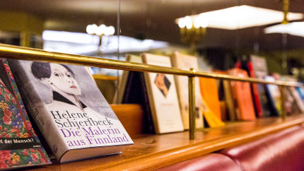 Nahaufnahme: Bücher auf einem Holzbord mit Messing-Reling.