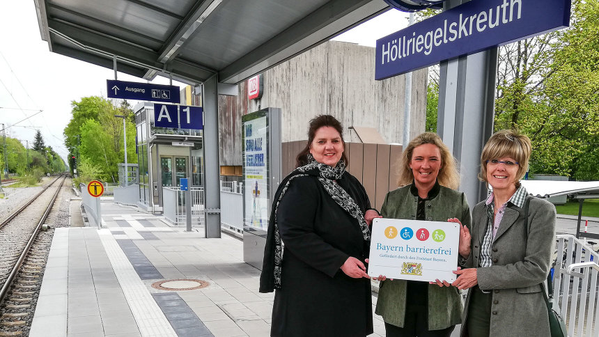 Gruppenbild: Übergabe des Signets „Bayern barrierefrei“ auf einem Bahnsteig.