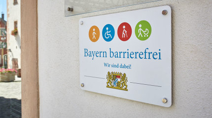 Das Signet „Bayern barrierefrei“ an einer Hauswand.