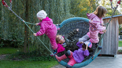 Lena und weitere Kita-Kinder in einer Nestschaukel.