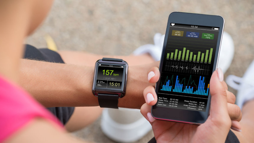 Eine Frau steuert ihr Fitness-Armband über eine Smartphone-App.