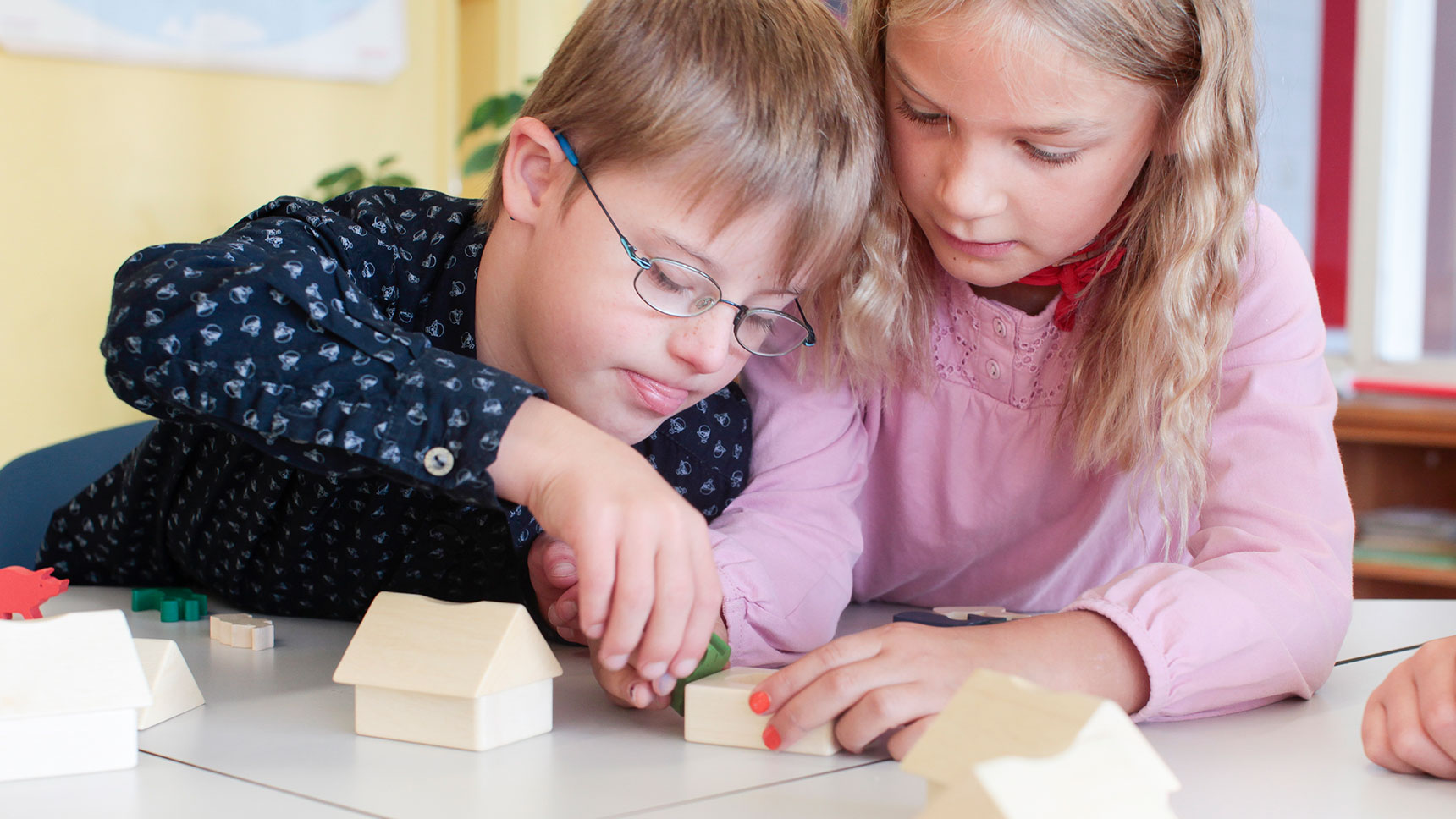 Zwei Kinder, eines mit geistiger Beeinträchtigung, spielen mit Bauklötzen.