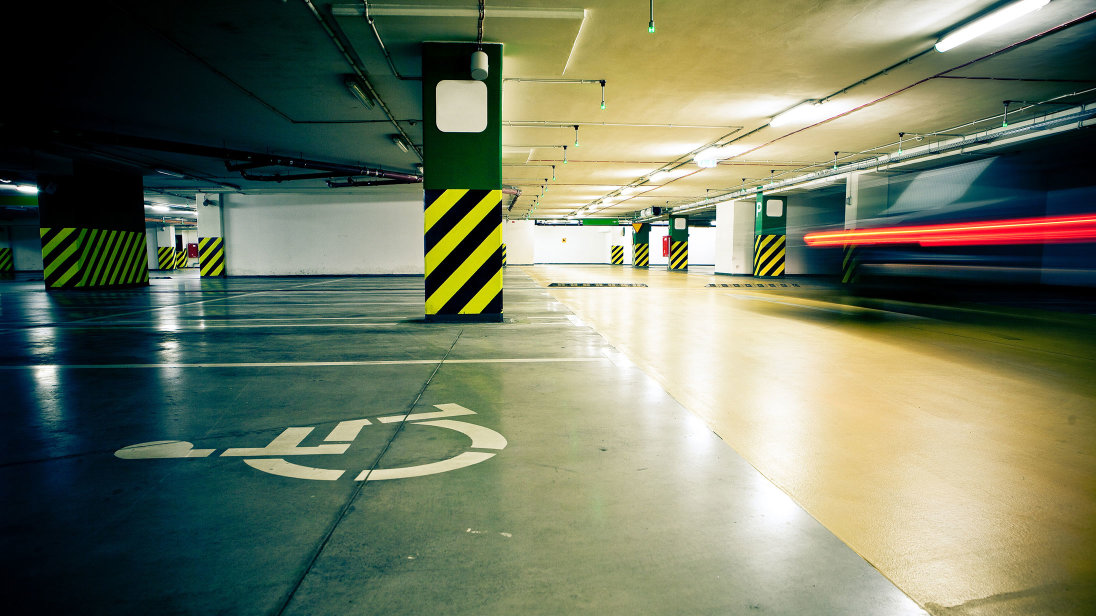 Behindertenparkplatz, erkennbar am Rollstuhl-Symbol auf der Parkfläche, in einer Tiefgarage.