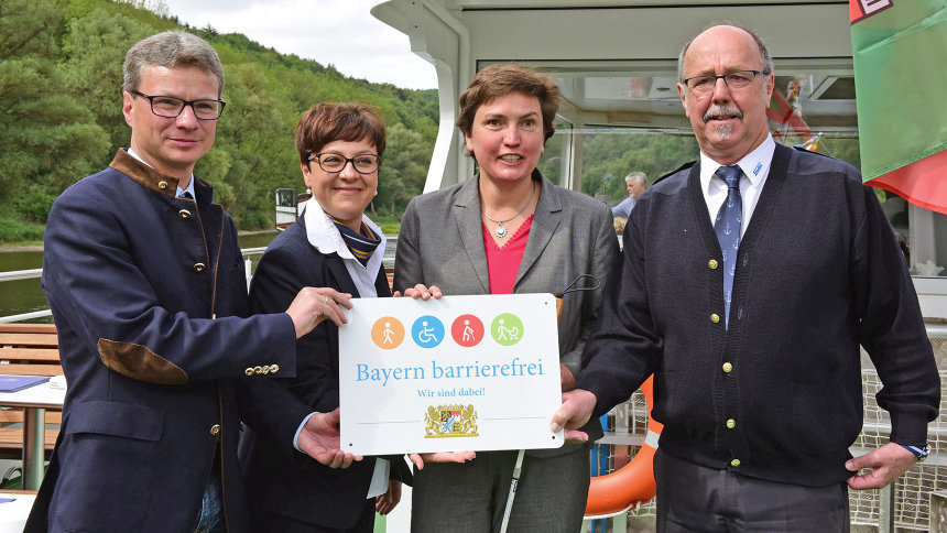 Gruppenbild: Übergabe des Signets „Bayern barrierefrei“ auf einem Schiff.