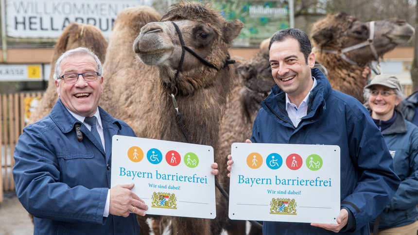 Übergabe des Signets „Bayern barrierefrei“; im Hintergrund: Kamele.