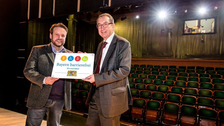 Übergabe des Signets „Bayern barrierefrei“ in einem Theatersaal.