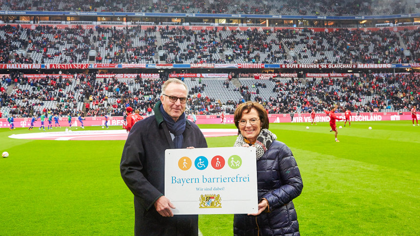 Im Fußballstadion: Sozialministerin Müller übergibt Signet „Bayern barrierefrei“ an Karl-Heinz Rummenigge.