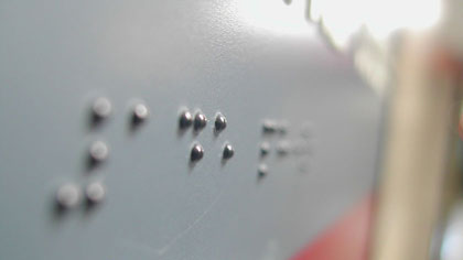 Tafel mit Braille-Schrift für Menschen mit Sehbehinderung.