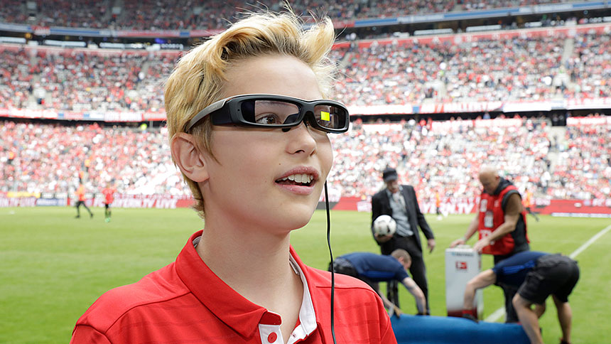 Junge mit digitaler Brille auf dem Spielfeld der Allianz Arena.
