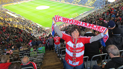 Martina B. im Stadion; sie hält einen Fanschal hoch.