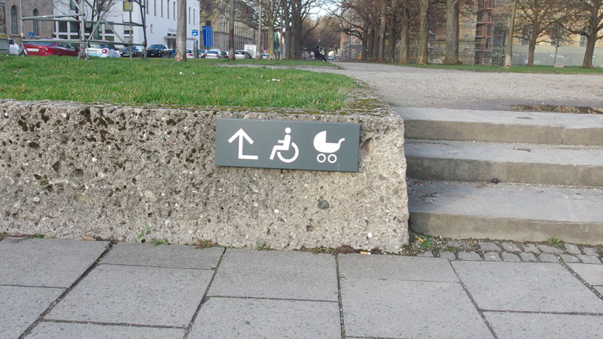Hinweisschild mit Rollstuhl- und Kinderwagen-Symbol.