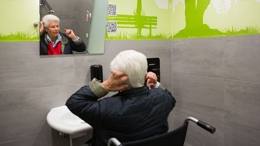 Doris B. vor dem Spiegel in der Behindertentoilette.