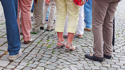 Gruppe älterer Menschen geht über Kopfsteinpflaster.