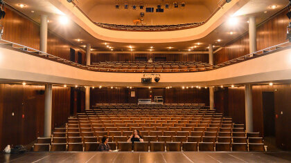 Blick von einer Theaterbühne in den Zuschauerraum mit Parkett und zwei Rängen.