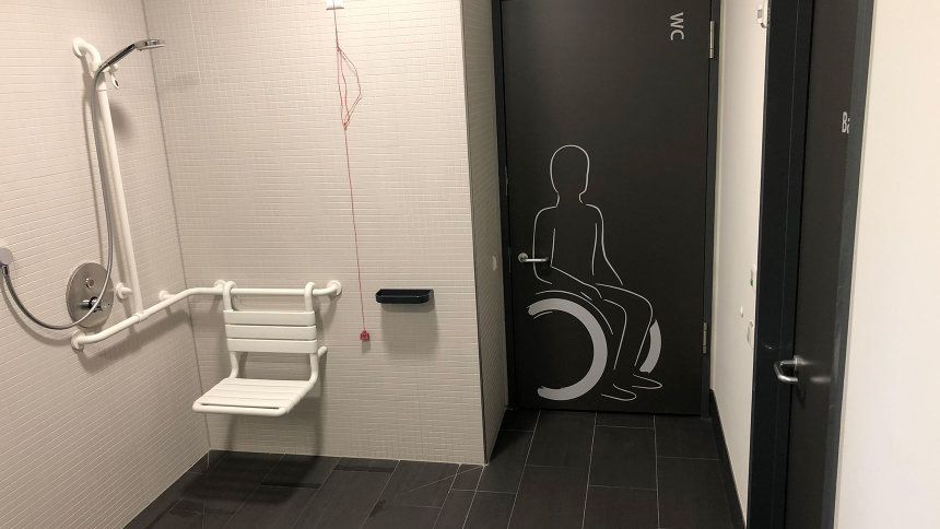Moderne Behindertenumkleide mit barrierefreier Dusche und WC.