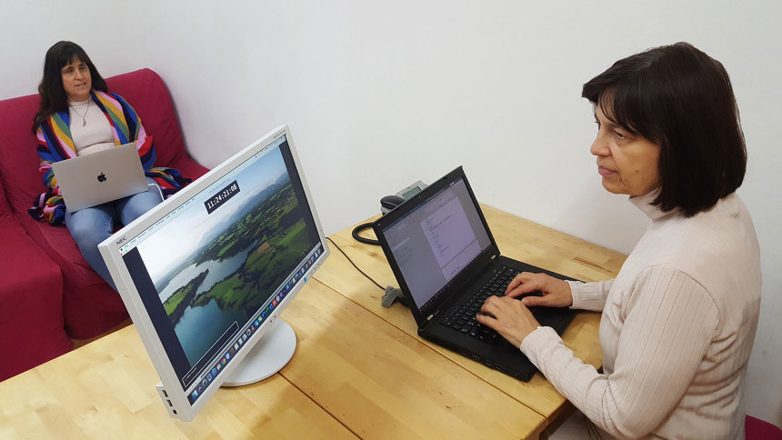 Elisabeth Löhmann sitzt mit Laptop und Bildschirm am Tisch, Manuela Schemm mit einem Laptop gegenüber. 