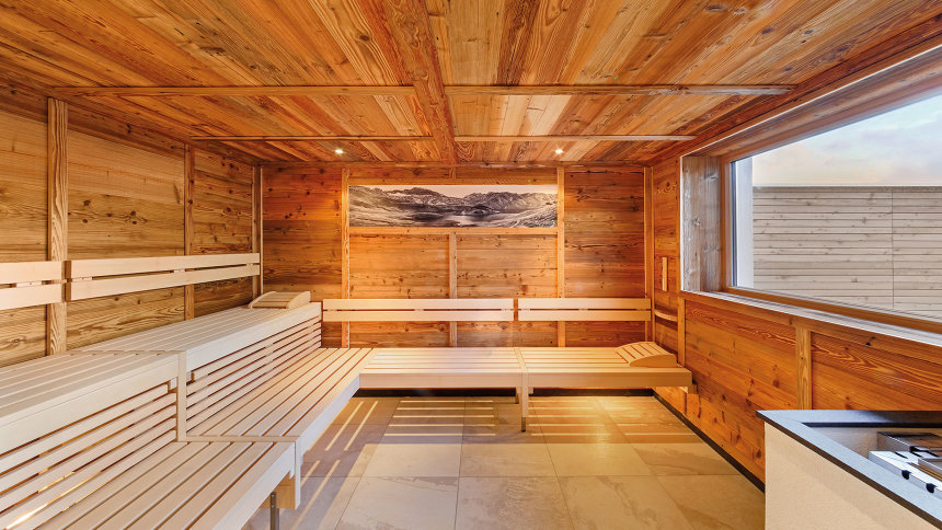 Blick in eine großräumige Sauna mit niedrigen Holzbänken.