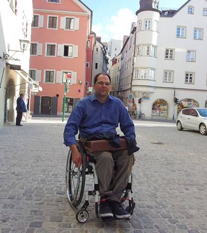 Florian Stangl im Rollstuhl auf einem ansteigenden, gepflasterten Weg.
