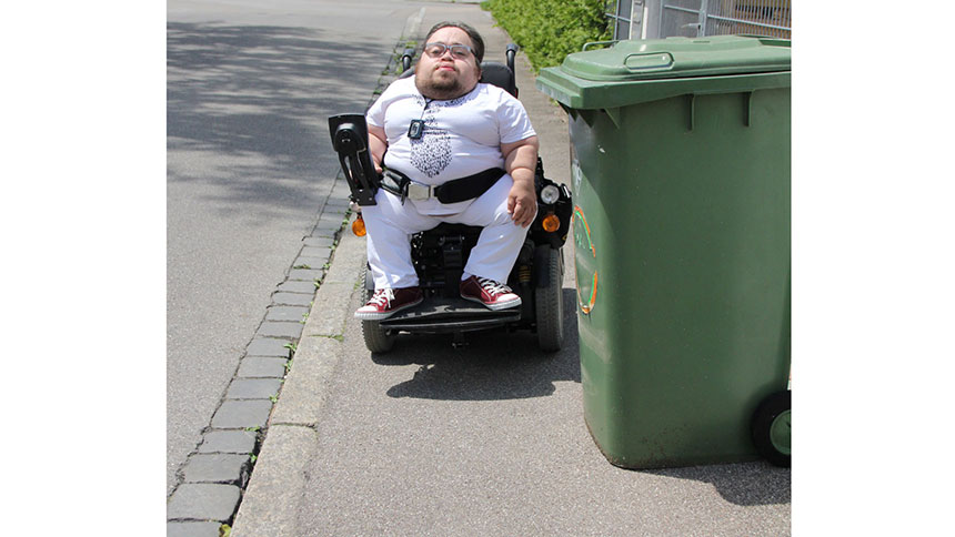 Benedikt Lika fährt auf einem schmalen Fußweg. Eine Mülltonne blockiert einen Teil des Wegs.