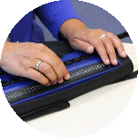 Nahaufnahme: Hände auf einer Braille-Zeile.
