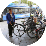 Irmgard Badura läuft an einer Reihe geparkter Fahrräder vorbei. Dabei streift sie ein Fahrrad, das aus der Reihe hervorragt.