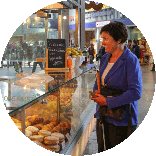 Irmgard Badura an der Theke eines Bäckerei-Verkaufsstandes in der Bahnhofshalle.