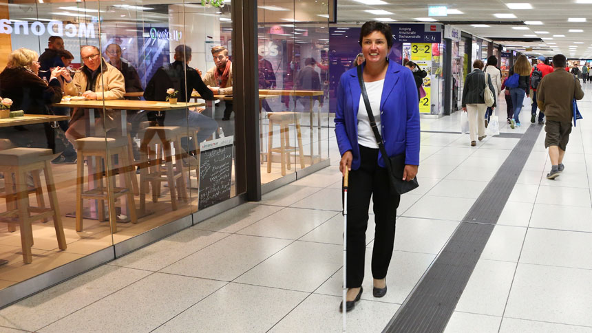 Irmgard Badura unterwegs im Bahnhofs-Zwischengeschoss. Sie folgt einem taktilen Leitsystem.