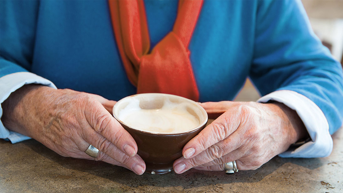 Ältere Dame mit einer Tasse Cappuccino.