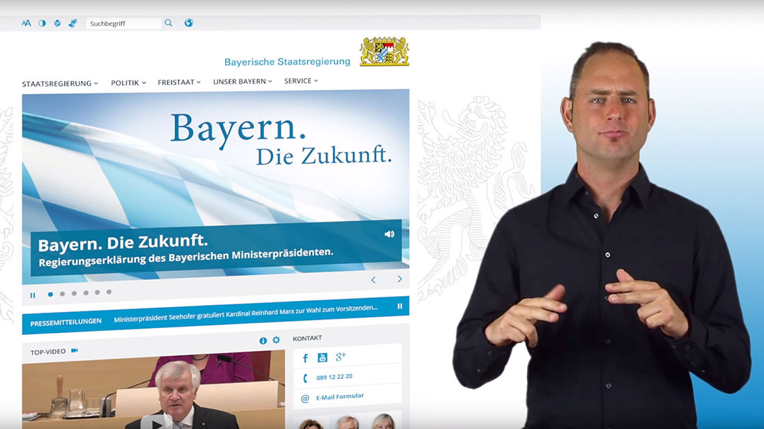 Website der Bayerischen Staatsregierung. Im Vordergrund ein Gebärdensprachdolmetscher.