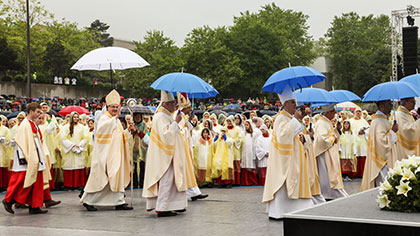Priester mit Regenschirmen auf dem Weg zur Bühne.