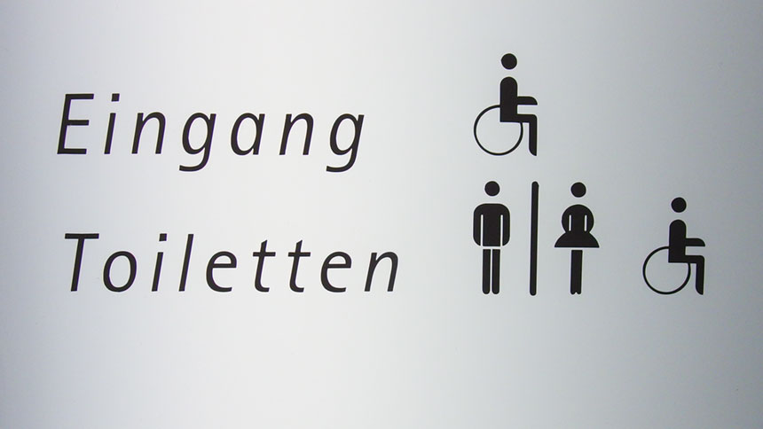 Wegweiser zu einem barrierefreien Eingang und zu (Behinderten-)Toiletten.