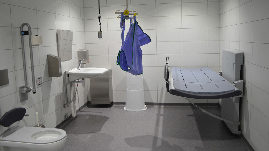 Eine „Toilette für alle“ mit Behinderten-WC, unterfahrbarem Waschbecken, Deckenlifter und Pflegeliege.