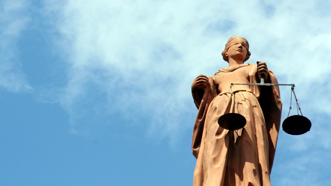 Statue der Justitia, dem antiken Symbol der Gerechtigkeit: eine Frauenfigur mit verbundenen Augen und einer Waage in der linken Hand.