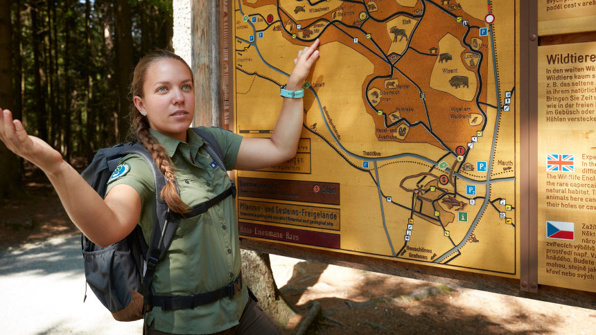 Rangerin Kristin Biebl vor Tafel mit einer Wanderkarte.