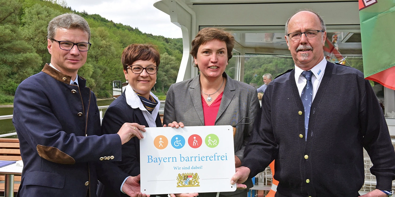 Gruppenbild: Übergabe des Signets „Bayern barrierefrei” auf einem Schiff.