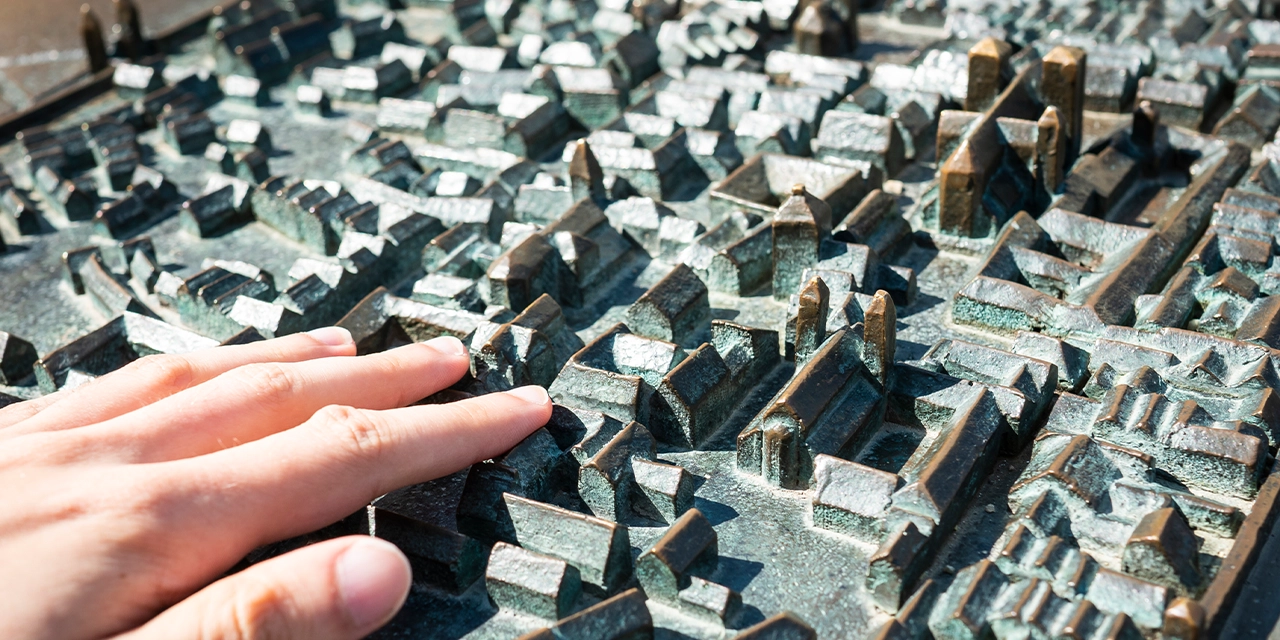 Eine Hand fährt über eine Miniaturstadt.