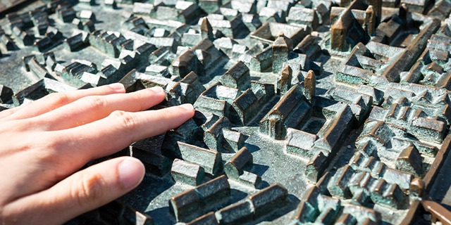 Eine Hand fährt über eine Miniaturstadt.