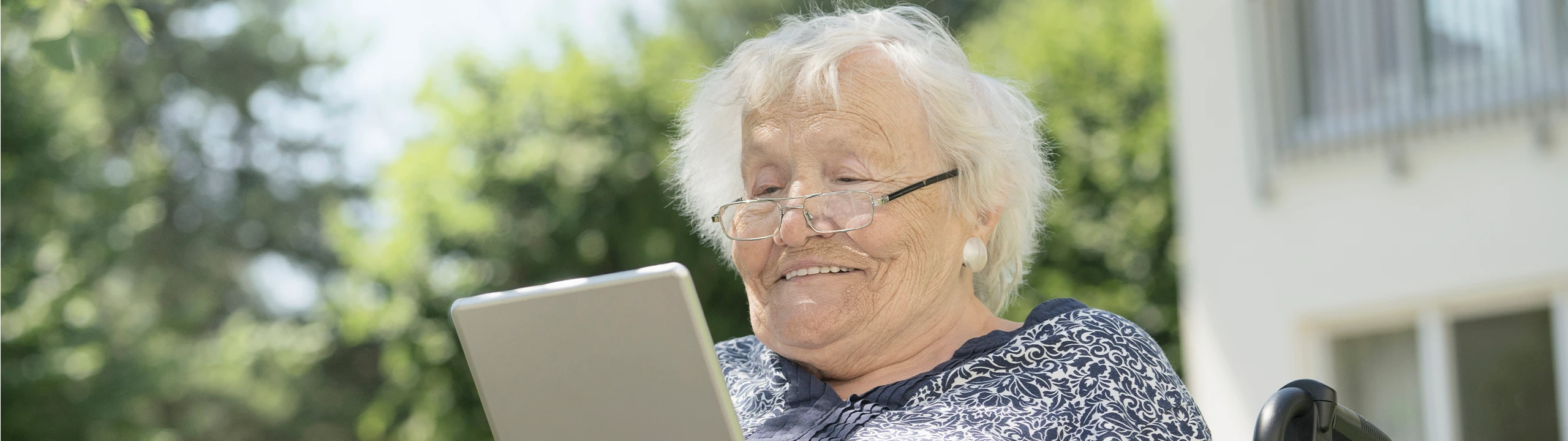 Eine ältere Frau blickt auf ein Tablet.