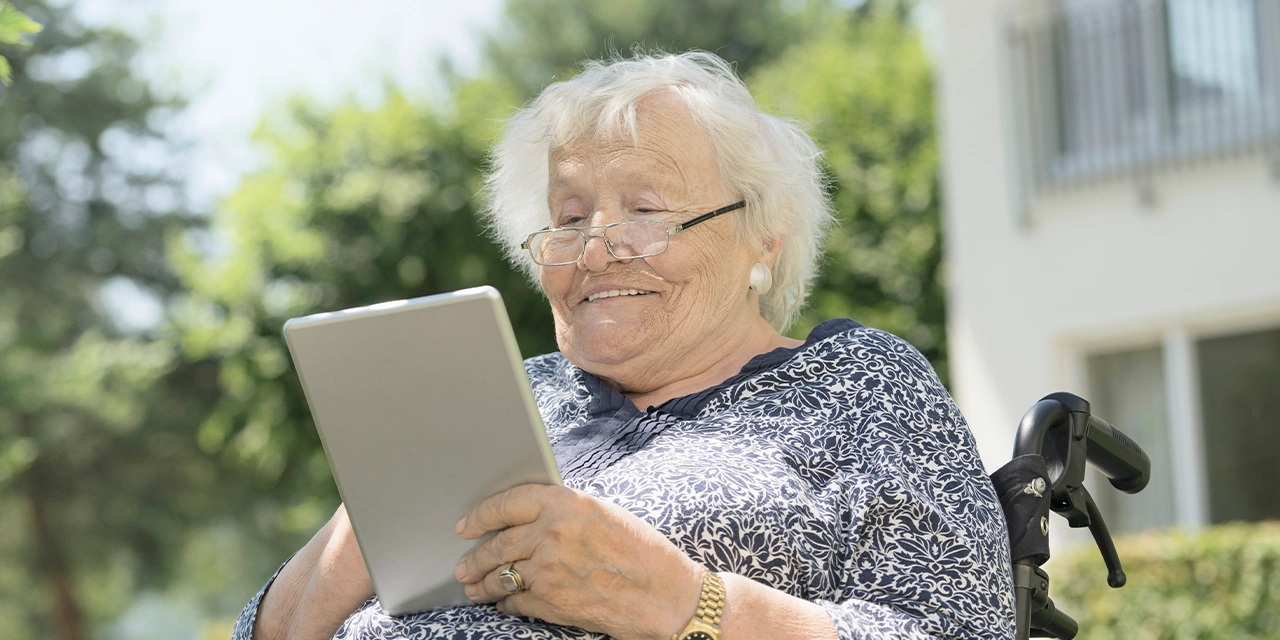 Eine ältere Frau blickt auf ein Tablet.