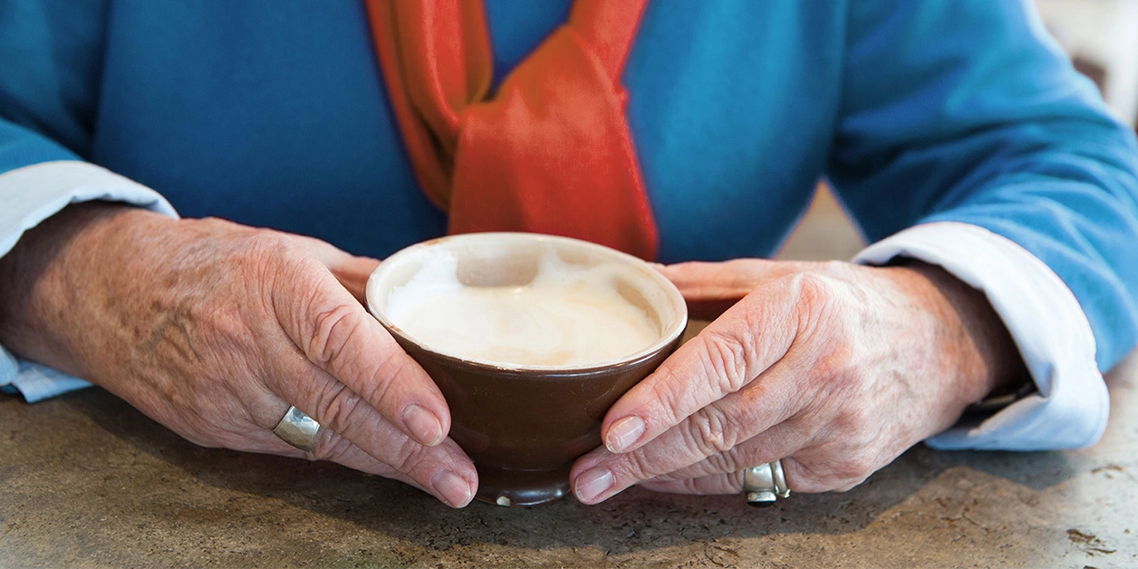Ältere Dame mit einer Tasse Cappuccino.