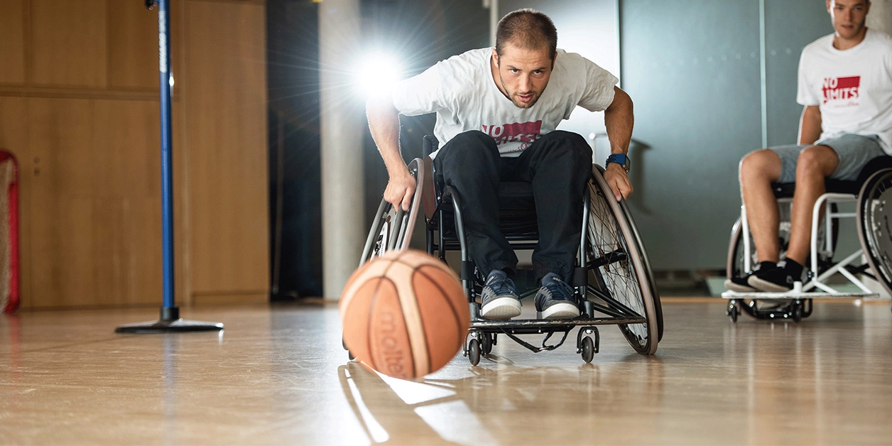 Ein Mann im Rollstuhl spielt Basketball.