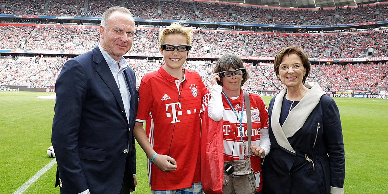 Gruppenfoto: hörbehinderte Fans in der Allianz Arena mit Sozialministerin Emilia Müller und Bayern-Chef Karl-Heinz Rummenigge.