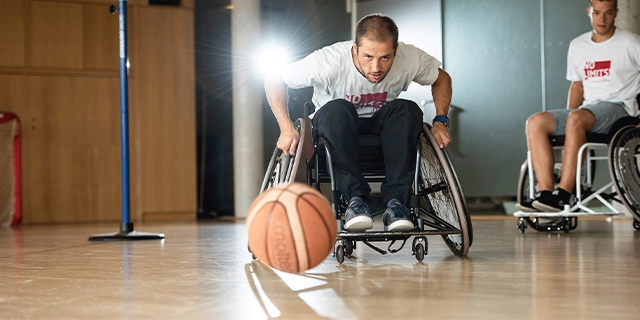 Ein Mann im Rollstuhl spielt Basketball.