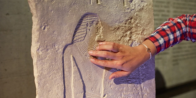 Hand einer Besucherin ertastet eine Relieffigur im Museum.