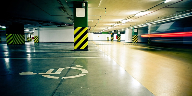Behindertenparkplatz, erkennbar am Rollstuhl-Symbol auf der Parkfläche, in einer Tiefgarage.