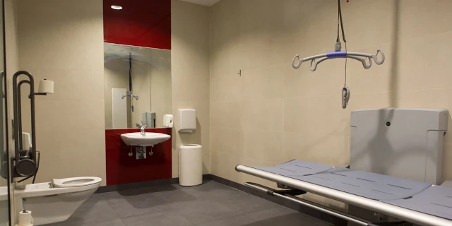 Innenraum einer Behindertentoilette mit Lifter und Liege.
