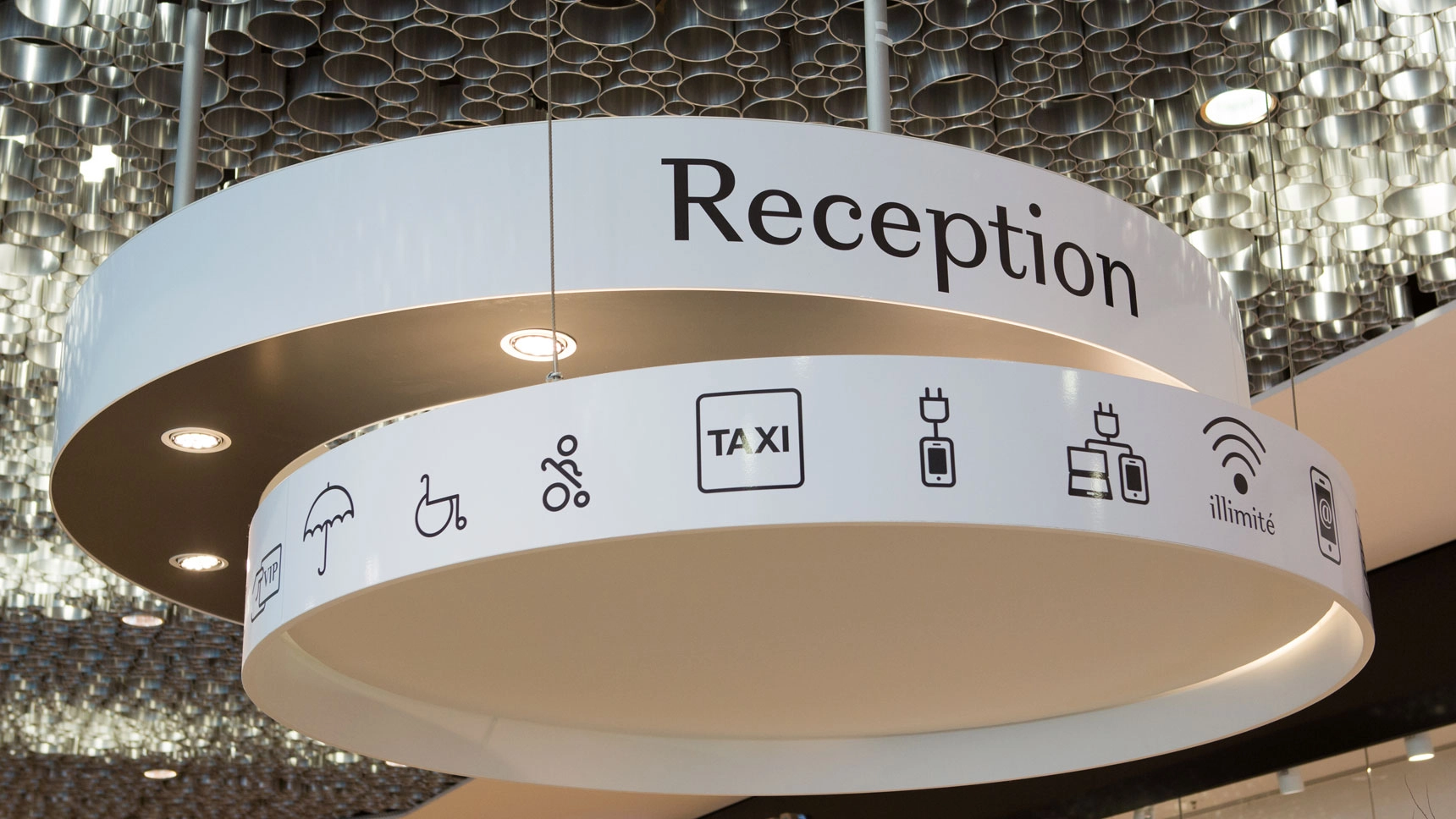 Deckenmodul über der Rezeption mit Signets, die verschiedene Services anzeigen.